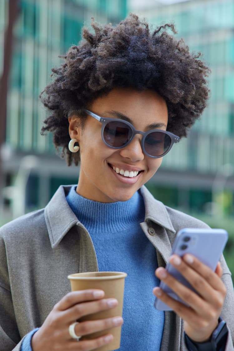 Woman enjoying coffee while using phone, representing financial freedom
